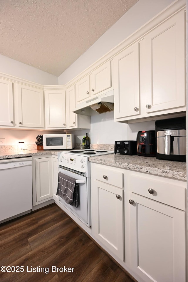 kitchen featuring dark hardwood / wood-style floors, light stone counters, a textured ceiling, and white appliances