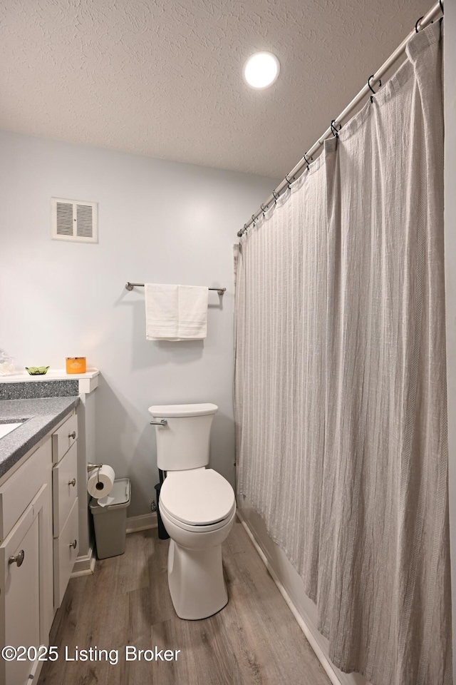 bathroom featuring hardwood / wood-style flooring, vanity, a textured ceiling, and toilet