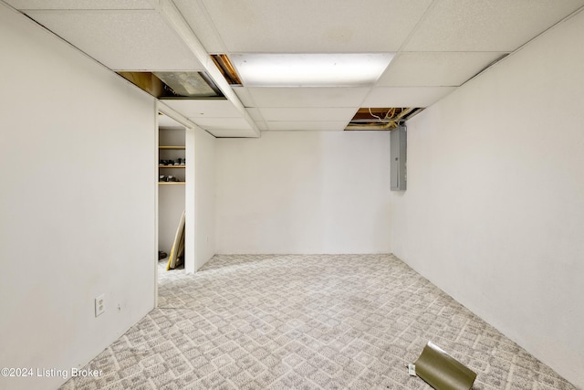 basement featuring light carpet, a drop ceiling, and electric panel