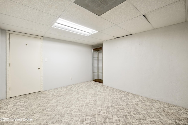 basement with a paneled ceiling and carpet