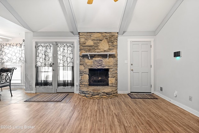 unfurnished living room featuring ceiling fan, wood-type flooring, and a stone fireplace