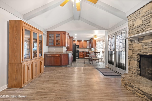 interior space featuring ceiling fan, hardwood / wood-style floors, vaulted ceiling with beams, tasteful backsplash, and black fridge