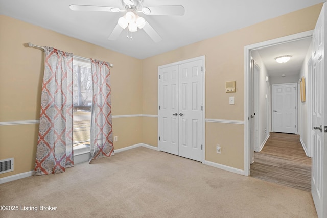 unfurnished bedroom with ceiling fan, a closet, and light carpet