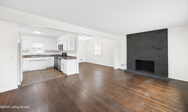 kitchen featuring range with electric cooktop, white cabinets, dark hardwood / wood-style flooring, white fridge, and a brick fireplace