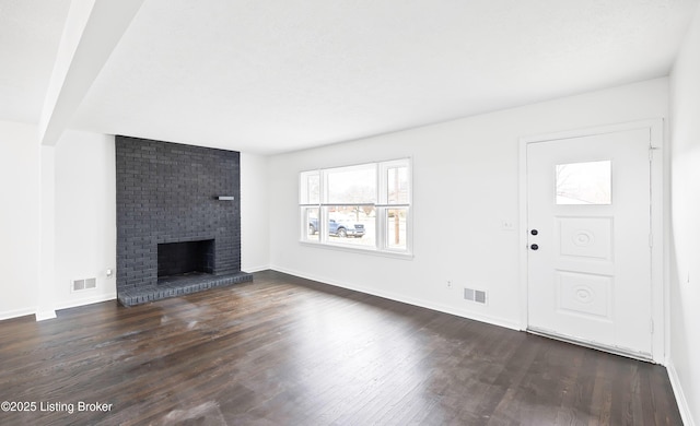 unfurnished living room with a brick fireplace and dark wood-type flooring