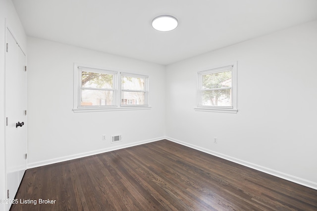 spare room with a wealth of natural light and dark hardwood / wood-style floors