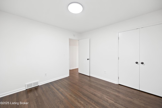 unfurnished bedroom with dark hardwood / wood-style flooring and a closet