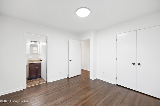 unfurnished bedroom featuring dark hardwood / wood-style floors, sink, ensuite bath, and a closet