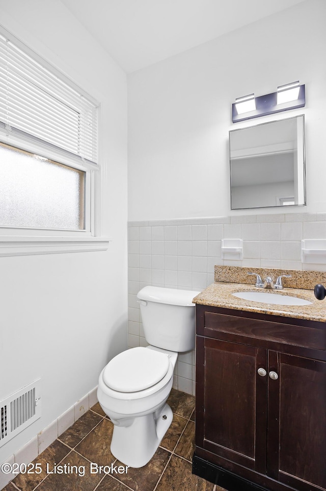 bathroom with tile patterned floors, vanity, toilet, and tile walls