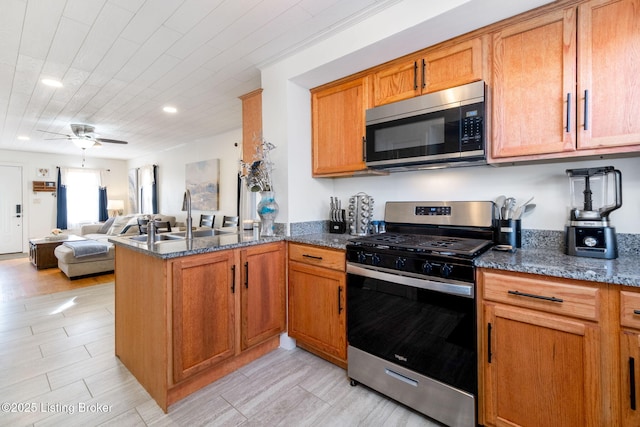 kitchen featuring appliances with stainless steel finishes, sink, dark stone countertops, and kitchen peninsula