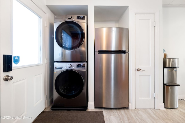 laundry area featuring stacked washer / dryer and light hardwood / wood-style floors