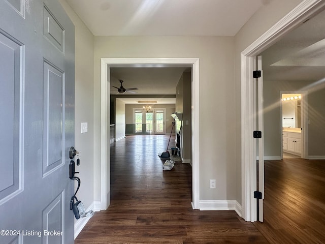 corridor featuring dark wood-type flooring and an inviting chandelier