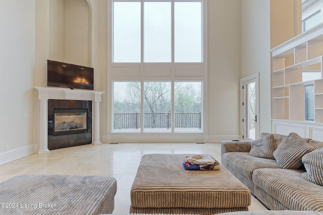 living room with a fireplace, light tile patterned floors, and a high ceiling