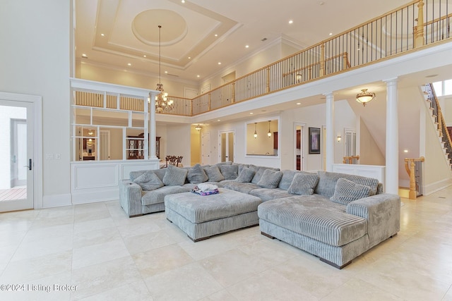 living room with light tile patterned floors, an inviting chandelier, a high ceiling, a raised ceiling, and ornate columns