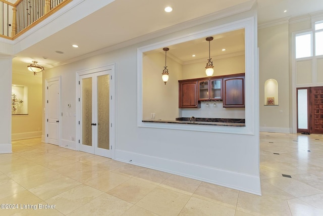 kitchen with pendant lighting, ornamental molding, kitchen peninsula, and a high ceiling