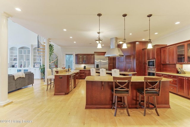 kitchen featuring decorative light fixtures, built in appliances, a kitchen breakfast bar, and a spacious island