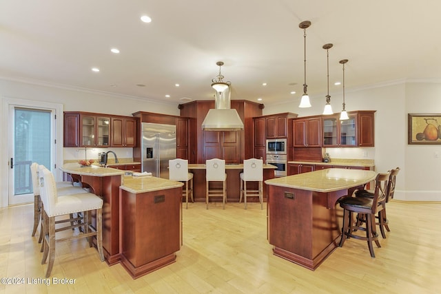 kitchen featuring a large island, a breakfast bar area, built in appliances, and hanging light fixtures