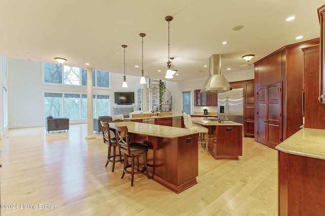 kitchen with a spacious island, a kitchen bar, light stone counters, pendant lighting, and stainless steel appliances