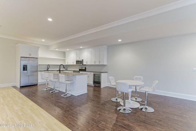 kitchen featuring white cabinetry, appliances with stainless steel finishes, a breakfast bar area, and a center island with sink