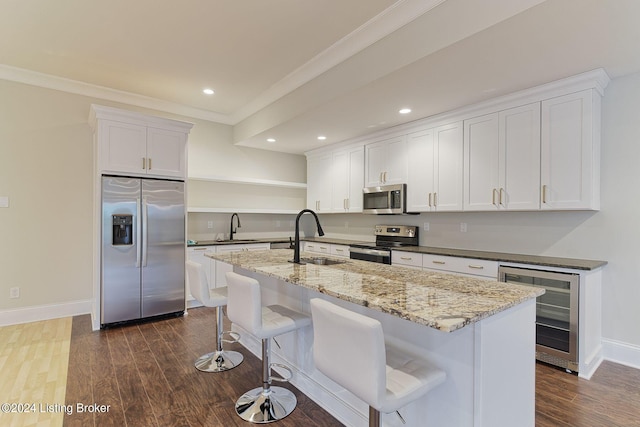 kitchen featuring sink, white cabinets, beverage cooler, a kitchen island with sink, and stainless steel appliances