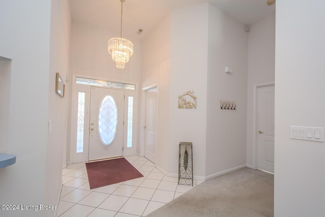 foyer entrance featuring light tile patterned floors, a towering ceiling, and a notable chandelier