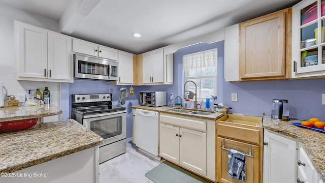 kitchen with light stone countertops, white cabinetry, appliances with stainless steel finishes, and sink