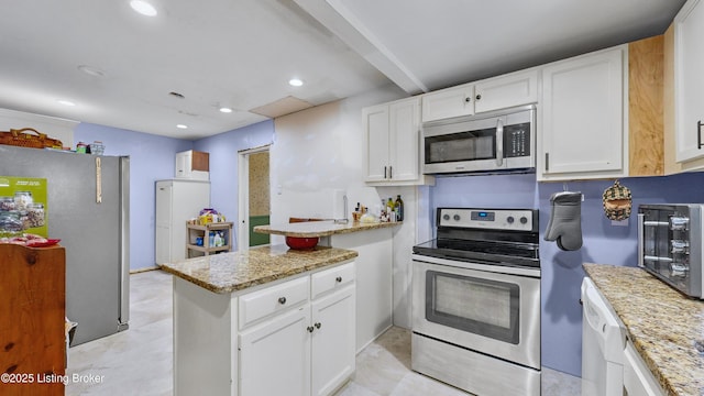 kitchen with light stone counters, stainless steel appliances, kitchen peninsula, and white cabinets