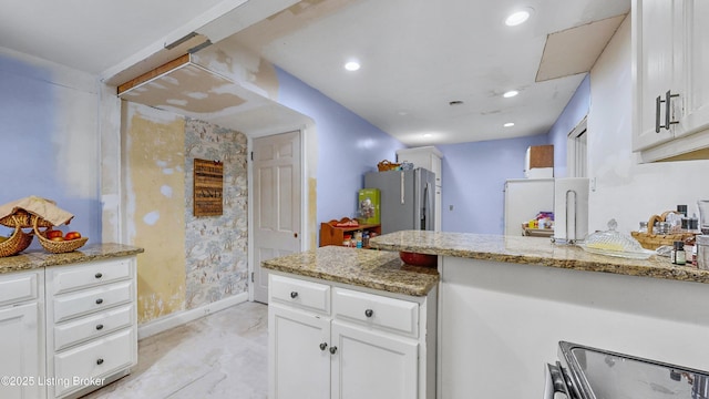 kitchen featuring white cabinetry, light stone counters, and stainless steel refrigerator