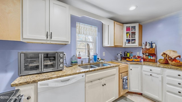 kitchen featuring white cabinetry, dishwasher, light stone countertops, and sink