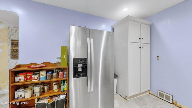 kitchen featuring stainless steel fridge and white cabinets