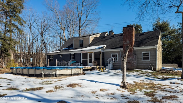 snow covered house with a sunroom and a covered pool