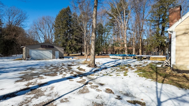 snowy yard with a garage and an outdoor structure