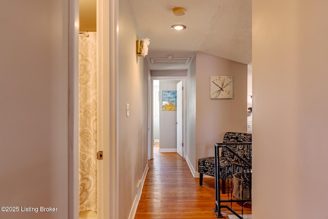 hallway featuring hardwood / wood-style flooring, lofted ceiling, and a textured ceiling