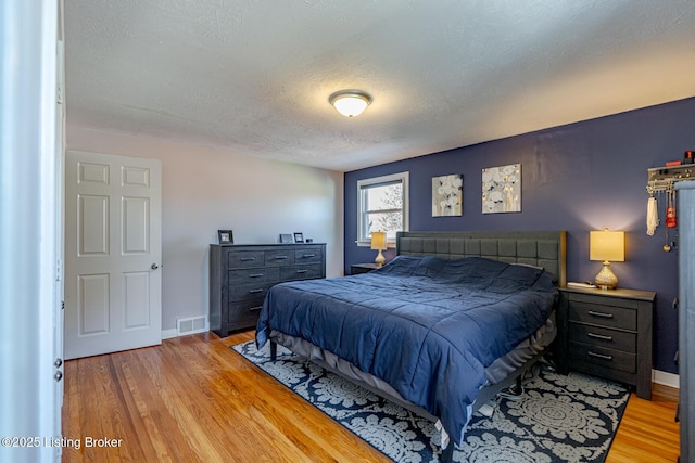 bedroom featuring light hardwood / wood-style floors and a textured ceiling