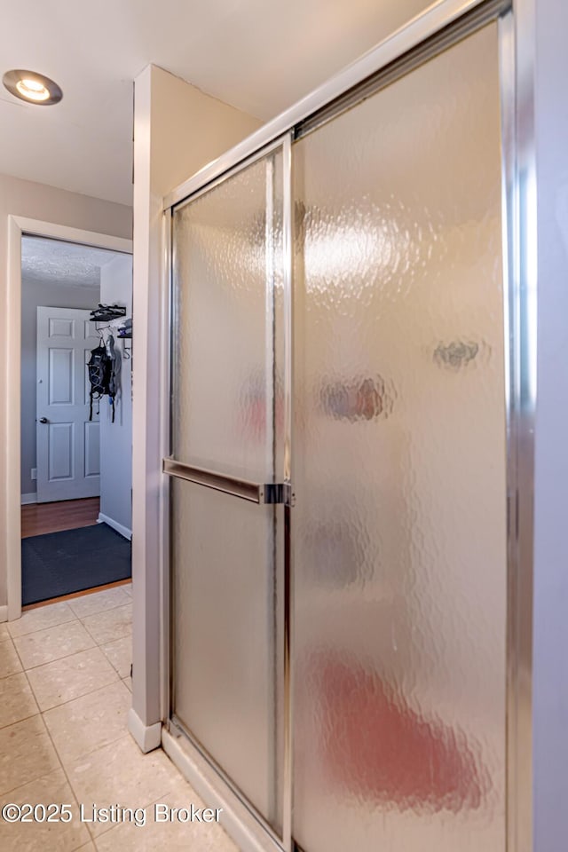 bathroom featuring a shower with shower door and tile patterned flooring