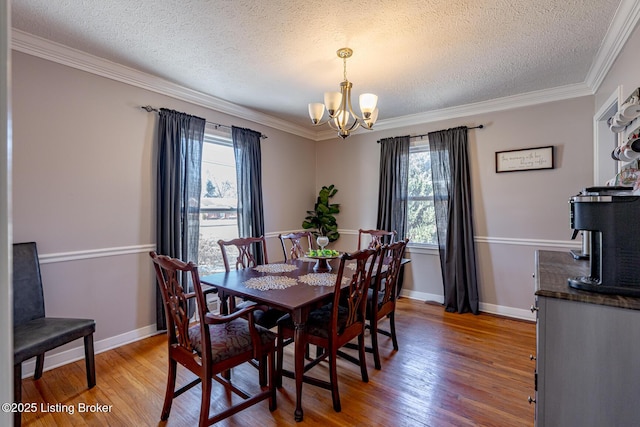 dining area with a wealth of natural light, a notable chandelier, a textured ceiling, and light hardwood / wood-style floors