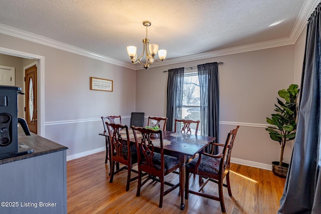 dining room featuring a notable chandelier, ornamental molding, and a textured ceiling