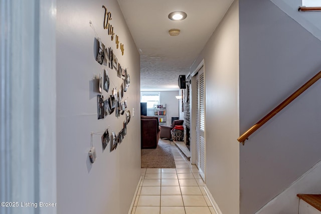 hallway featuring light tile patterned floors and a textured ceiling