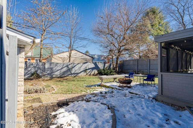 yard layered in snow with an outdoor fire pit and a sunroom