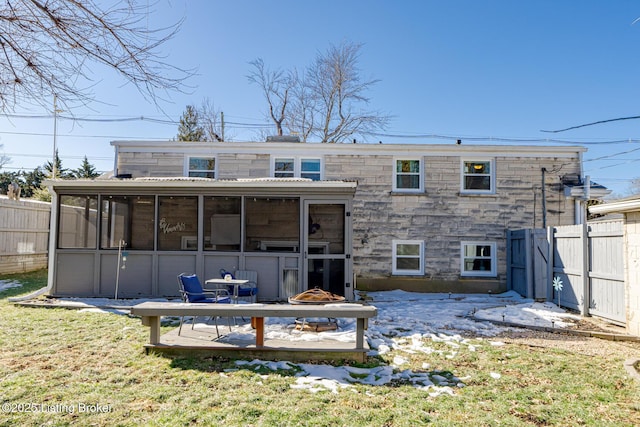 rear view of property featuring an outdoor fire pit, a sunroom, and a lawn