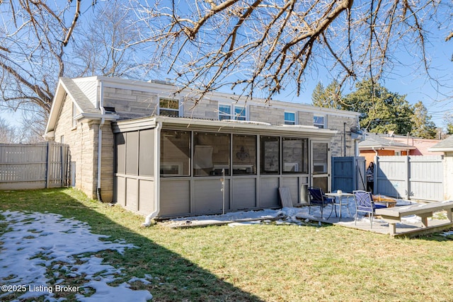 back of property featuring a sunroom, a patio area, and a lawn