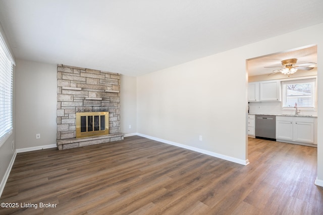 unfurnished living room featuring dark hardwood / wood-style floors, ceiling fan, a fireplace, and sink