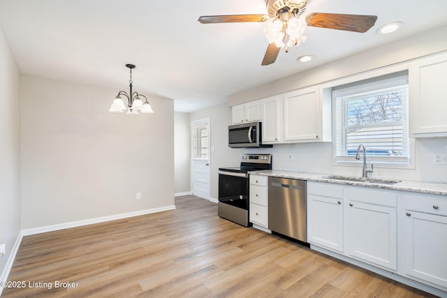 kitchen with pendant lighting, sink, white cabinets, backsplash, and stainless steel appliances