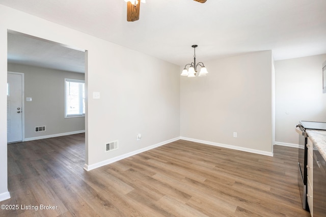 unfurnished dining area featuring wood-type flooring and ceiling fan with notable chandelier