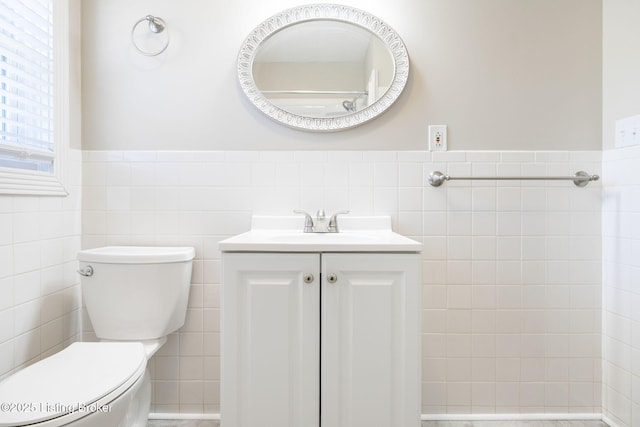 bathroom with vanity, toilet, and tile walls