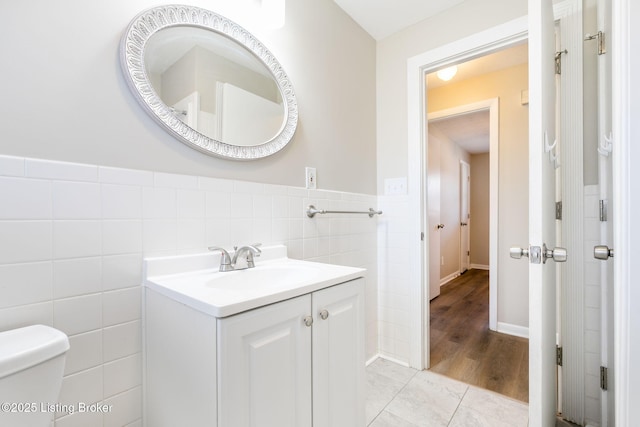 bathroom with tile patterned floors, vanity, toilet, and tile walls