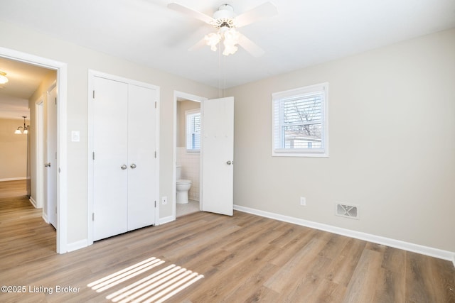 unfurnished bedroom with connected bathroom, light hardwood / wood-style flooring, ceiling fan, and a closet