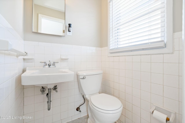 bathroom with tile walls, sink, and toilet