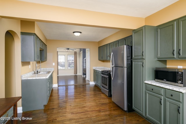 kitchen with stainless steel appliances, sink, green cabinets, and dark wood-type flooring