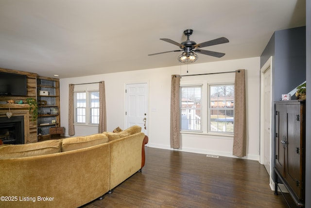 living room with dark hardwood / wood-style flooring, ceiling fan, and a fireplace